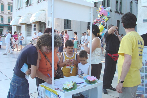 Prolaznici potpisuju peticiju i promatraju Falun Gong vježbe